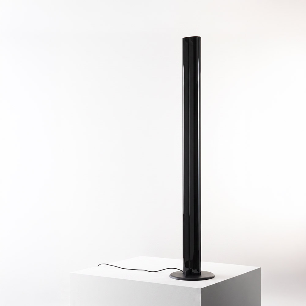 Artemide Megaron floor lamp: tall slender black cylindrical column with circular base, emitting indirect light from vertical slit