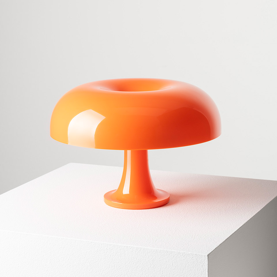 Lampada da tavolo Artemide Nessino arancione, con paralume lucido a forma di ciambella su una base a piedistallo snello