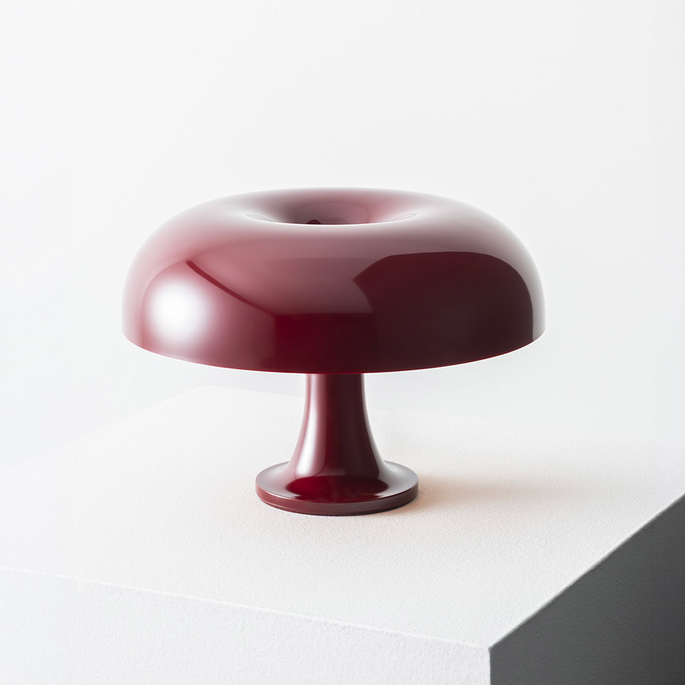 Lampada da tavolo Artemide Nessino in rosso bordeaux, con paralume lucido a forma di ciambella su una base a piedistallo sottile