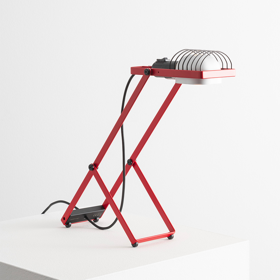 Lampada da tavolo Artemide Sintesi rossa con struttura a forbice in metallo, paralume riflettore bianco con griglia protettiva e cavo nero