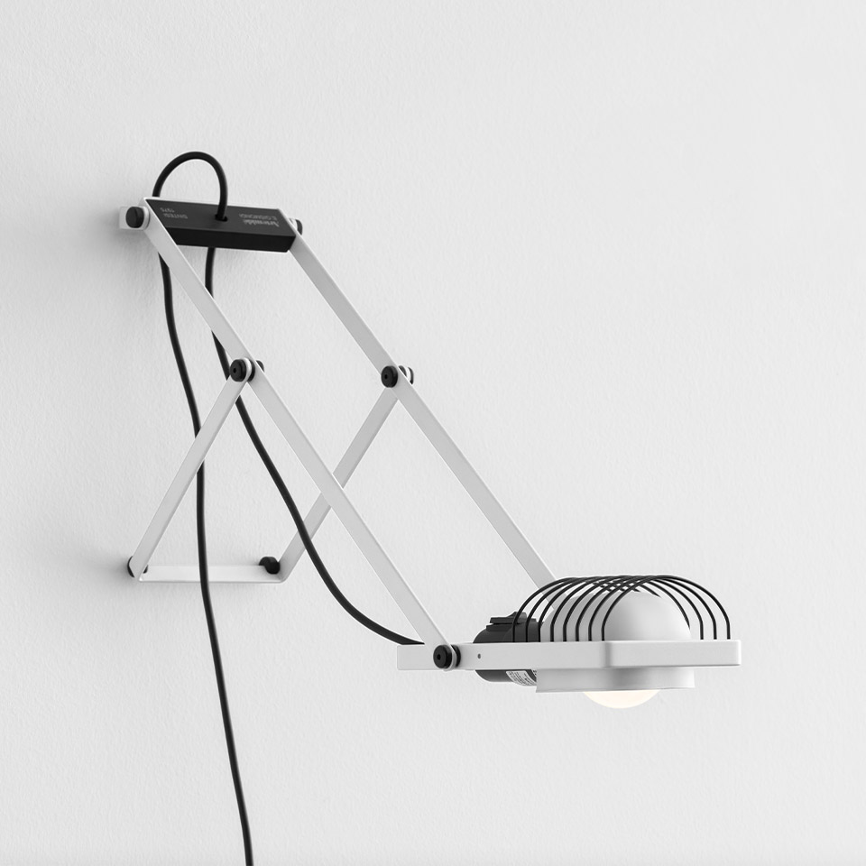 Lampada da parete Artemide Sintesi: struttura bianca articolata a pantografo con paralume a griglia metallica a cupola, montata a parete con cavo nero