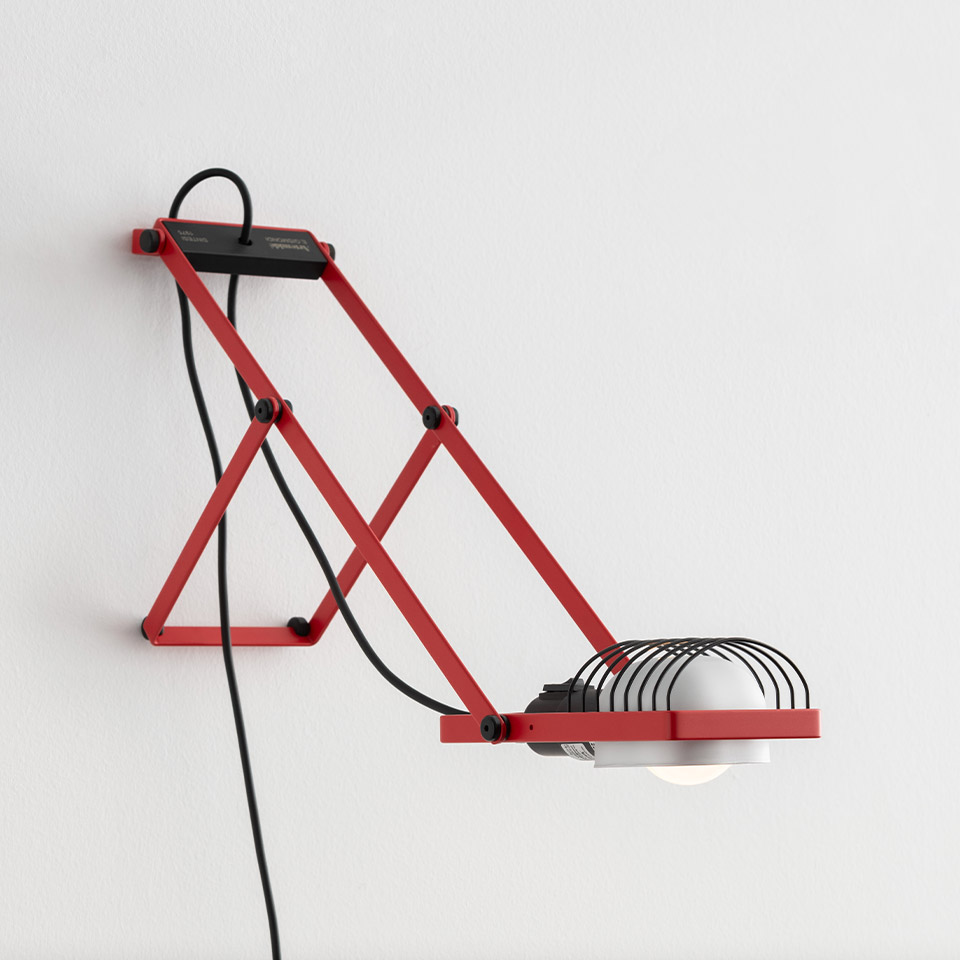 Lampada da parete Artemide Sintesi rossa con braccio articolato a forbice, paralume a gabbia nera e cavo elettrico nero a vista