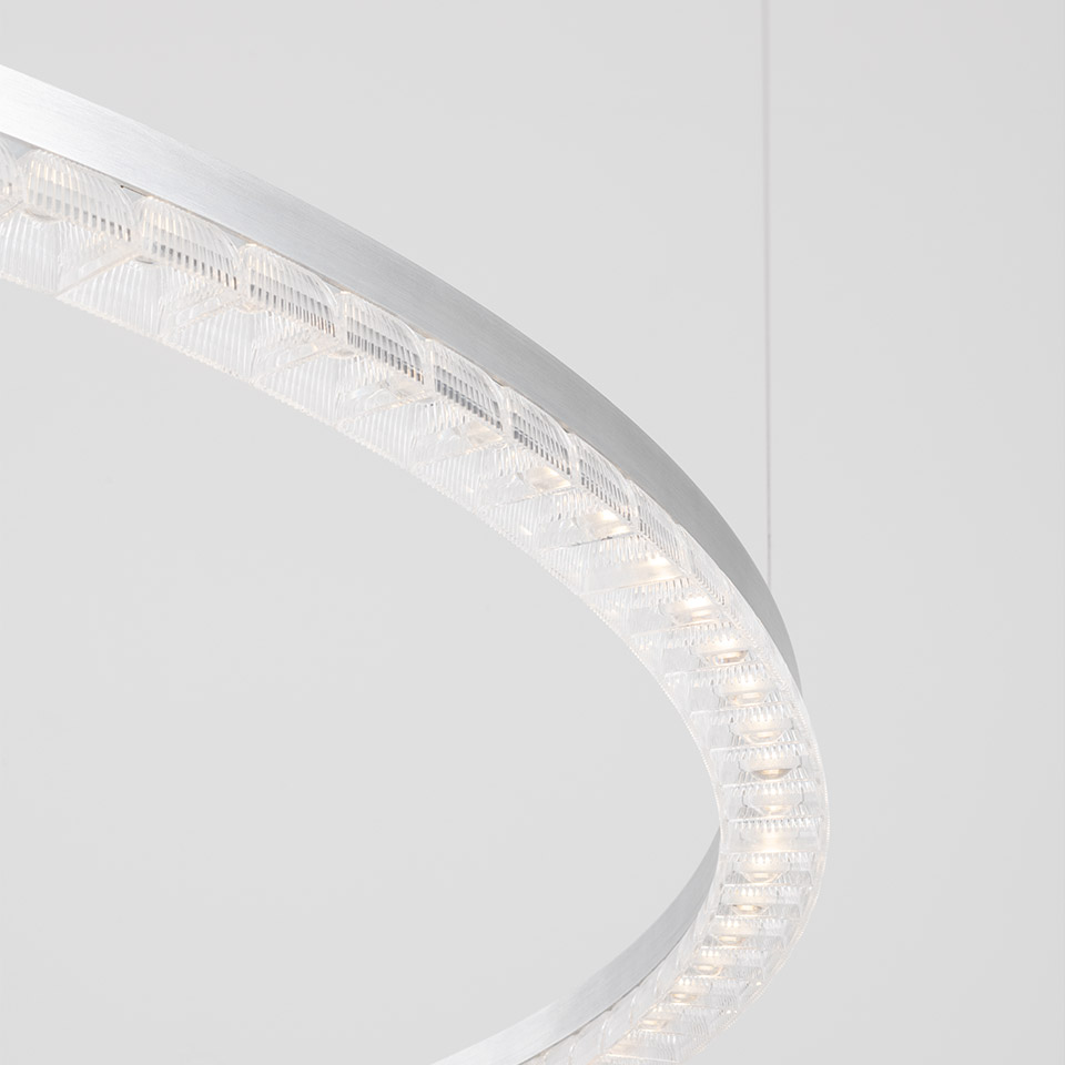 Lampada a sospensione Artemide Somnĭum: primo piano dell'anello circolare in alluminio con moduli LED in cristallo prismatico che emettono luce bianca calda
