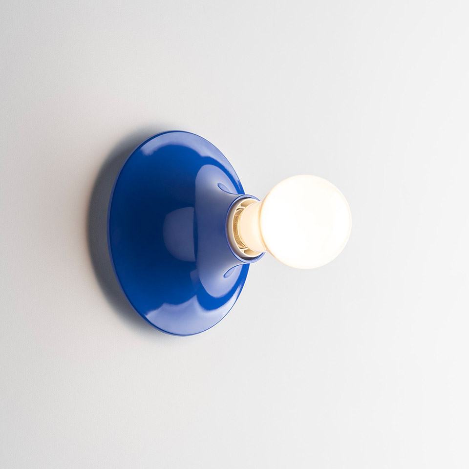 Artemide Teti wall lamp with cobalt blue glossy oval base and exposed spherical white bulb mounted on white wall