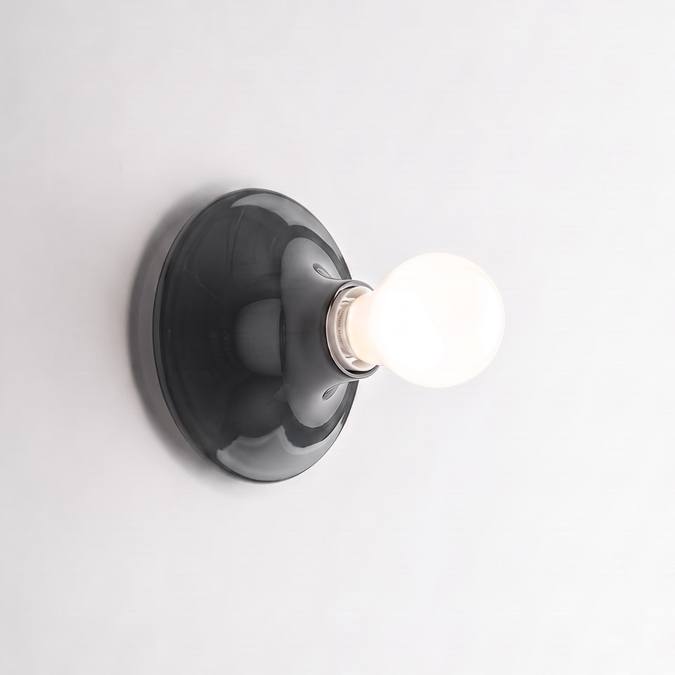 Artemide Teti wall lamp: glossy dark grey ceramic disc base with exposed frosted globe bulb, minimalist design
