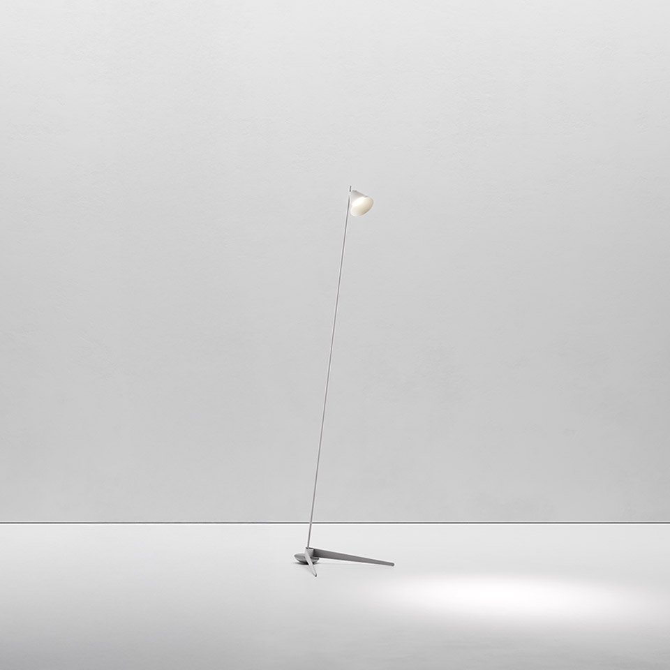 Lampada da terra Artemide Vea: stelo sottile inclinato con piccolo diffusore sferico bianco su base minimale a tre punte, con luce soffusa verso il basso