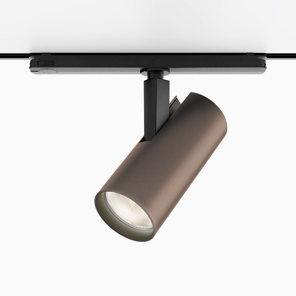 Faretto Artemide Vector Track 230V in finitura bronzo, corpo cilindrico montato su binario nero, LED direzionale orientabile