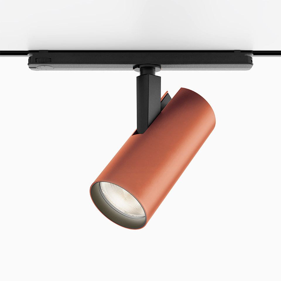 Faretto Artemide Vector Track 230V in rosso terracotta, corpo cilindrico su binario nero, spot LED orientabile