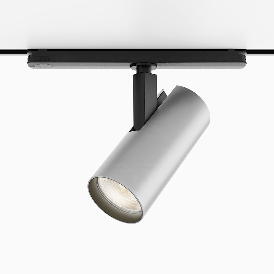 Artemide Vector Track 230V: faretto cilindrico argento montato su binario nero, testa orientabile con sorgente luminosa LED