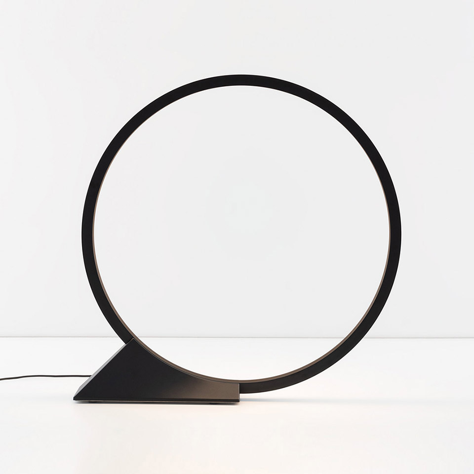 Lampada da tavolo Artemide O: anello LED circolare nero su base triangolare, design geometrico minimalista