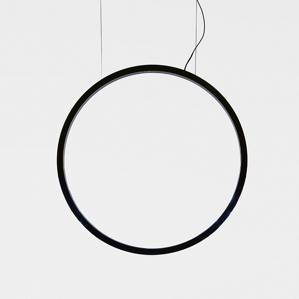 Lampada a sospensione Artemide O: grande anello circolare nero con LED integrato, sospeso da sottili cavi neri su sfondo bianco