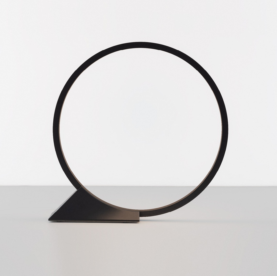 Lampada da tavolo Artemide 'O': anello LED circolare nero minimalista bilanciato su una base triangolare in metallo scuro