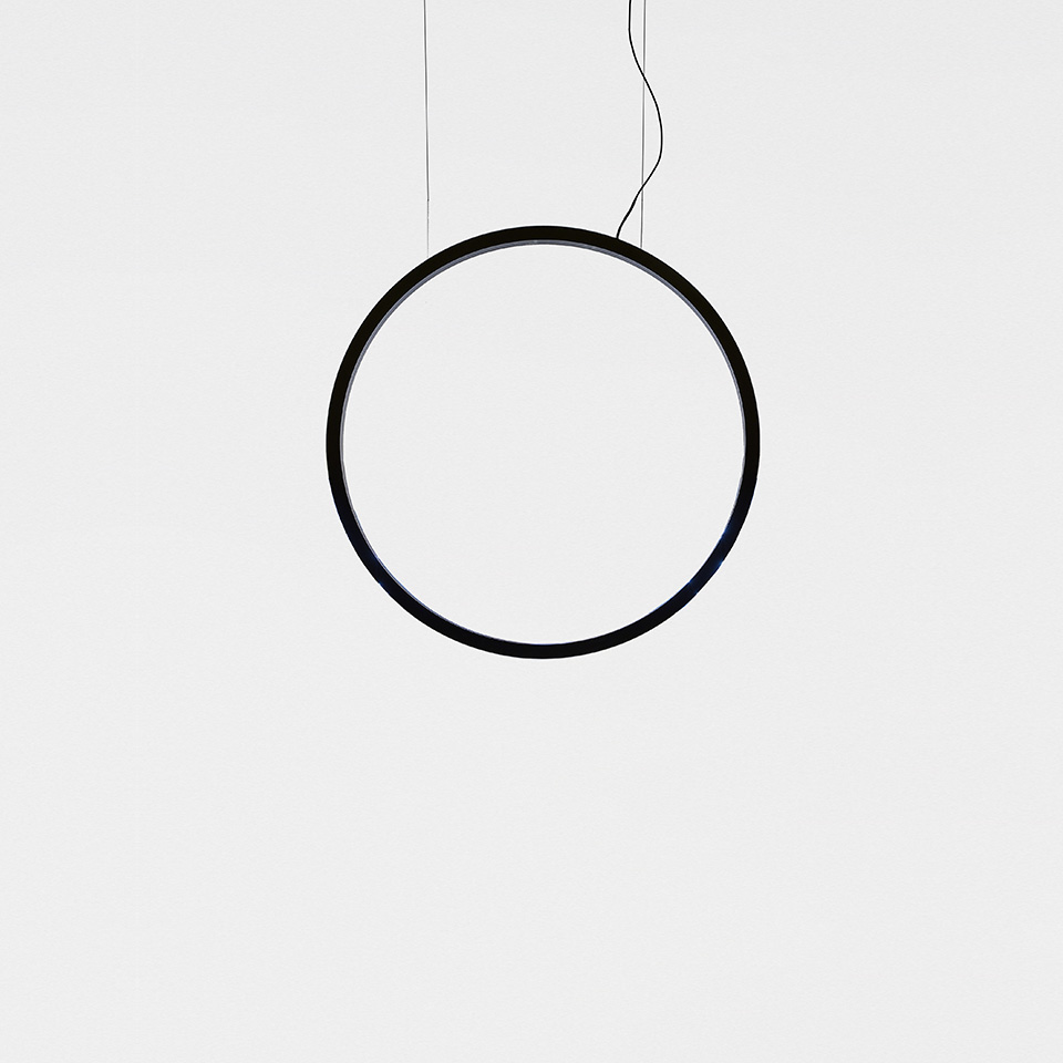 Lampada a sospensione Artemide 'O': anello circolare nero minimalista sospeso da sottili cavi su sfondo bianco