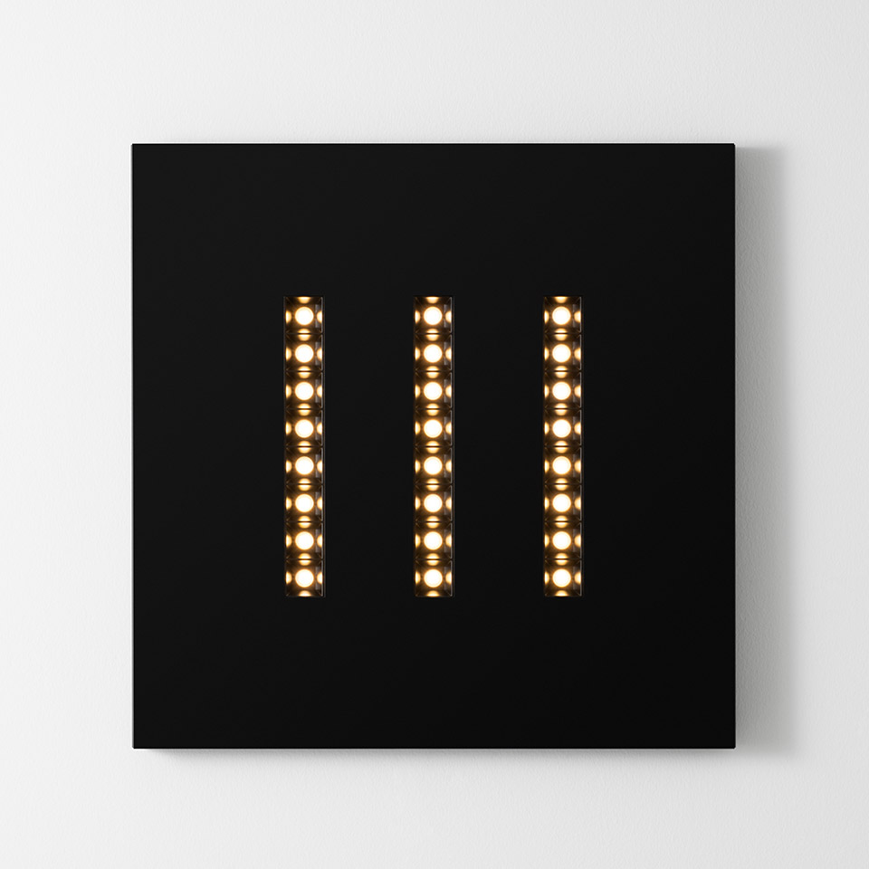 Lampada da parete Artemide A.39 Refractive Square: pannello quadrato nero con tre strisce LED verticali che emettono luce bianca calda