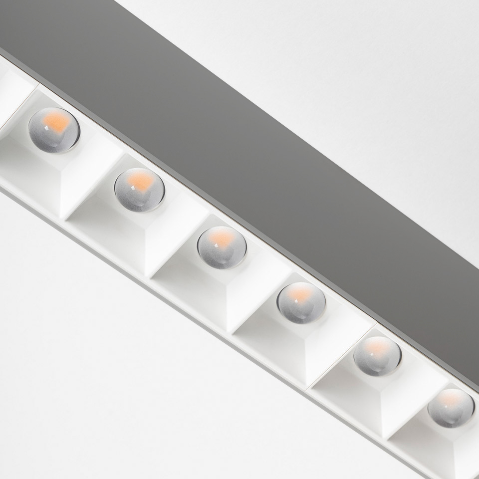 Primo piano del soffitto Artemide A.39 con una fila di sei lenti LED refrattive a luce calda in alloggiamenti quadrati bianchi su profilo lineare