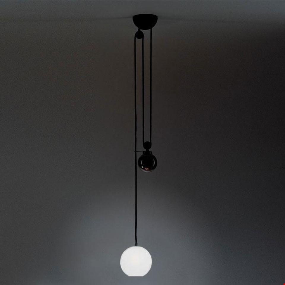 Artemide Aggregato pendant lamp with opal white glass sphere diffuser, black cord, and counterweight pulley system on dark ceiling