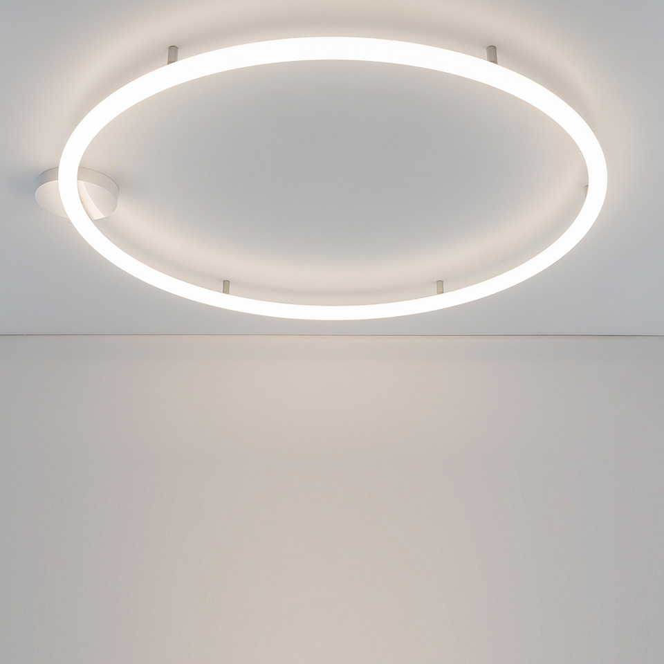 Lampada da soffitto Artemide Alphabet of Light Circular: grande anello luminoso bianco montato a filo su soffitto bianco, emette luce diffusa morbida