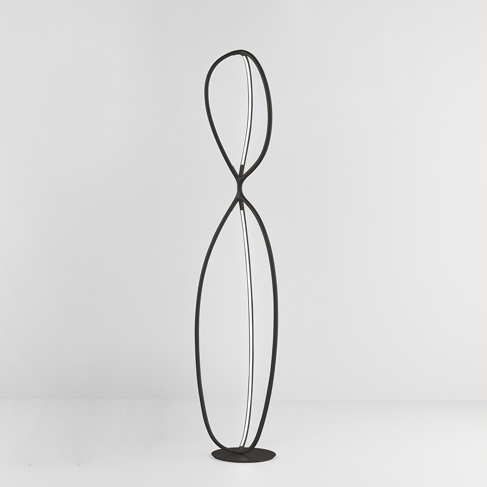 Lampada da terra Artemide Arrival: alta struttura in metallo nero con due anelli intrecciati a formare una silhouette a clessidra con strisce LED integrate