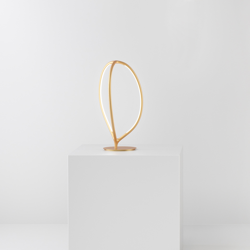 Lampada da tavolo Artemide Arrival in finitura oro, con elegante struttura LED a doppia curva a forma di foglia su base circolare