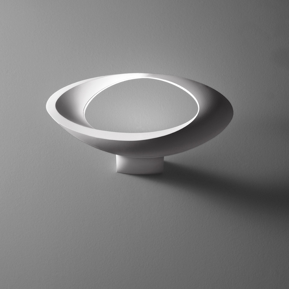 Artemide Cabildo wall lamp: white elliptical disc-shaped diffuser with circular LED ring, mounted on a small cylindrical base