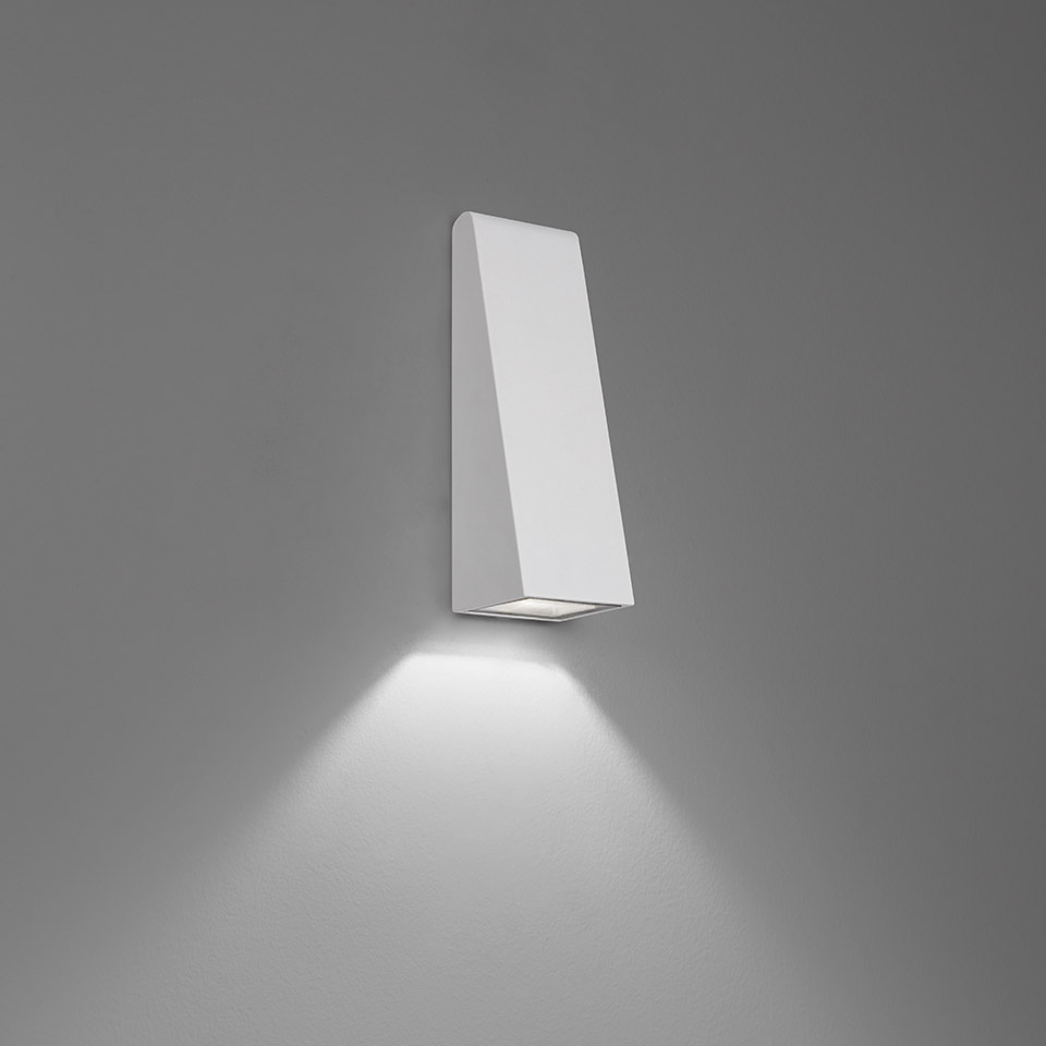 Applique Artemide Cuneo: corpo trapezoidale bianco a parete con fascio LED orientato verso il basso