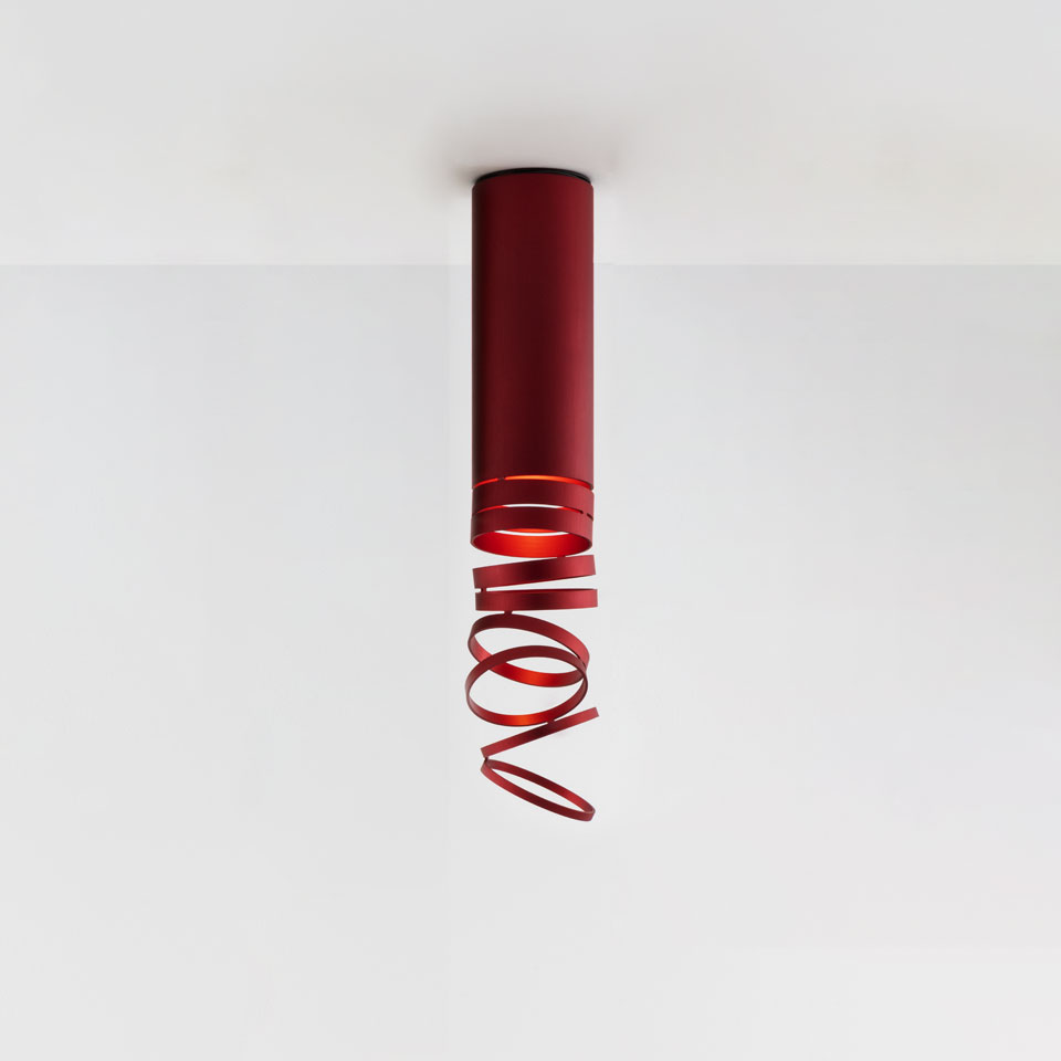Artemide Decomposé Light Soffitto ceiling lamp in red, featuring a cylindrical body with a decorative spiraling metal ribbon diffuser