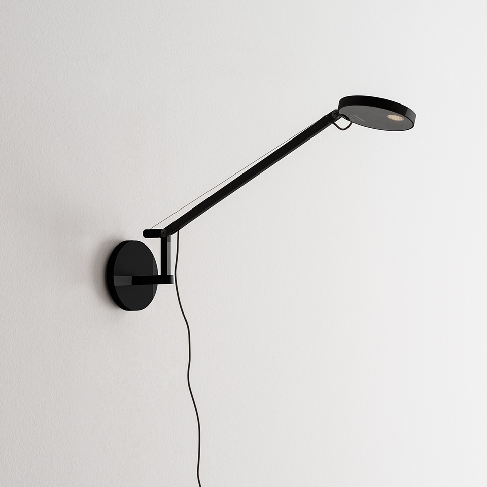 Artemide Demetra Micro Parete wall lamp in black, featuring an adjustable arm and flat circular LED head mounted on a round wall base.
