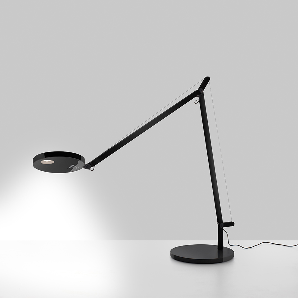 Lampada da tavolo Artemide Demetra nera, con braccio regolabile, testa LED circolare e base rotonda che proietta luce concentrata.