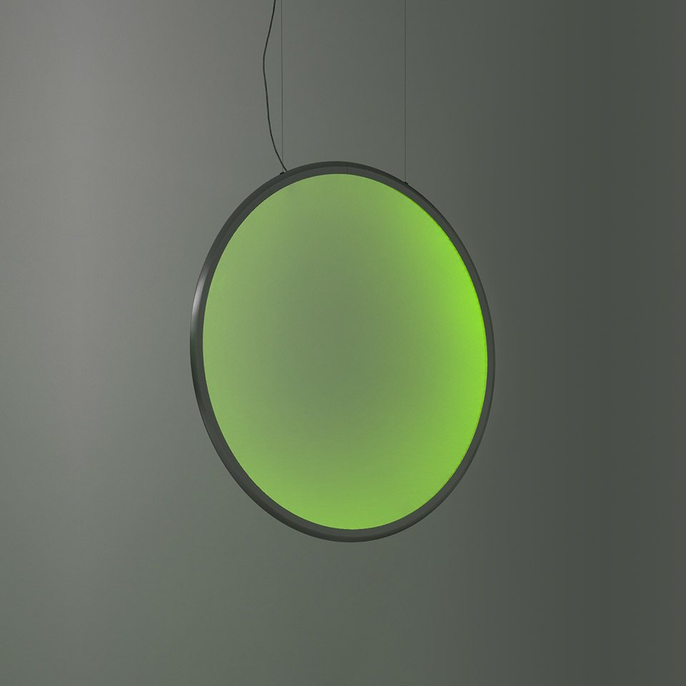 Lampada a sospensione Artemide Discovery: grande disco circolare che emette luce verde vibrante, cornice in metallo scuro, sospesa da sottile cavo nero