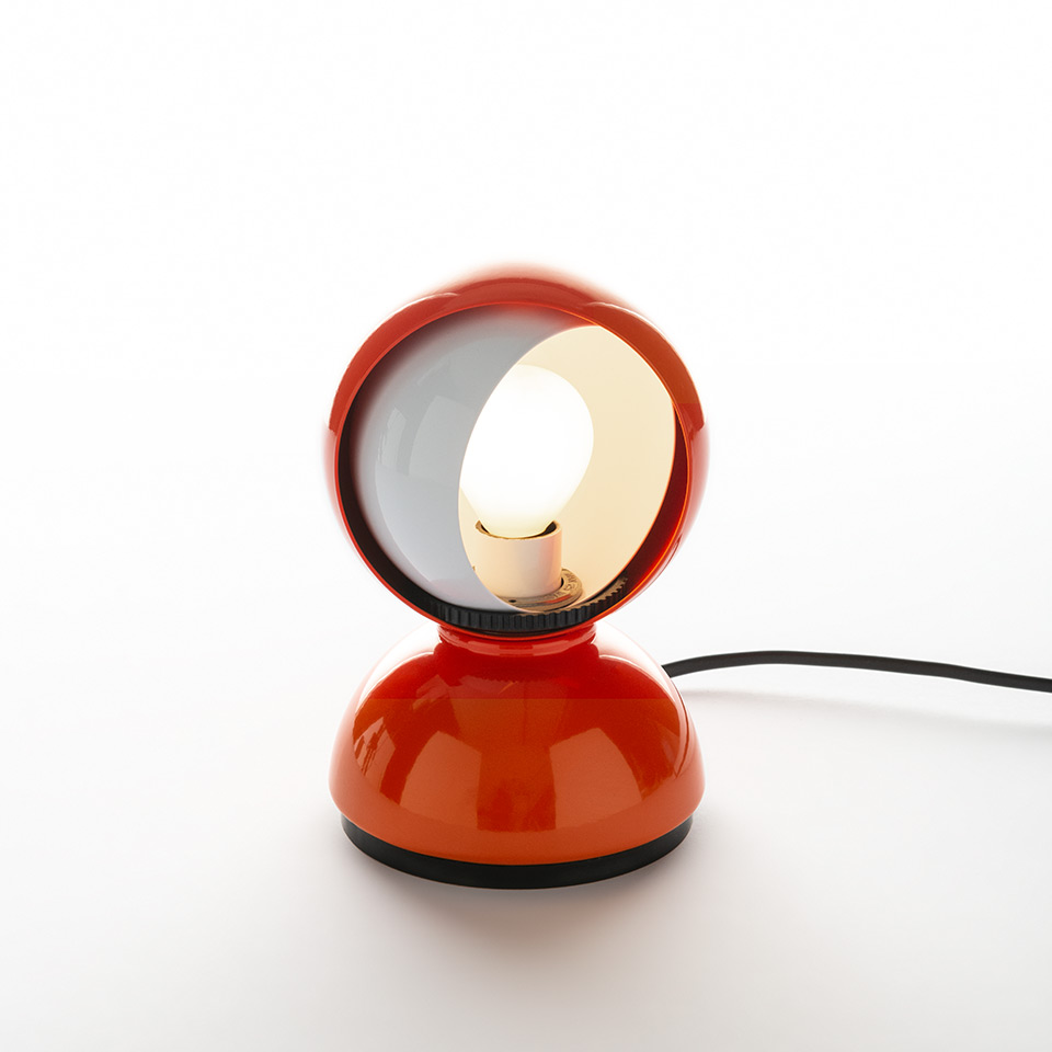 Artemide Eclisse table lamp in orange, featuring a rotating spherical shade on a dome-shaped base, with bulb visible