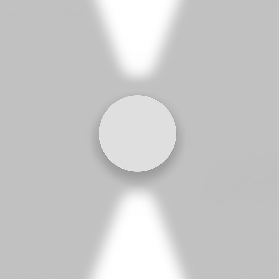 Applique Artemide Effetto: corpo circolare bianco che emette due fasci di luce verso l'alto e il basso su parete grigia