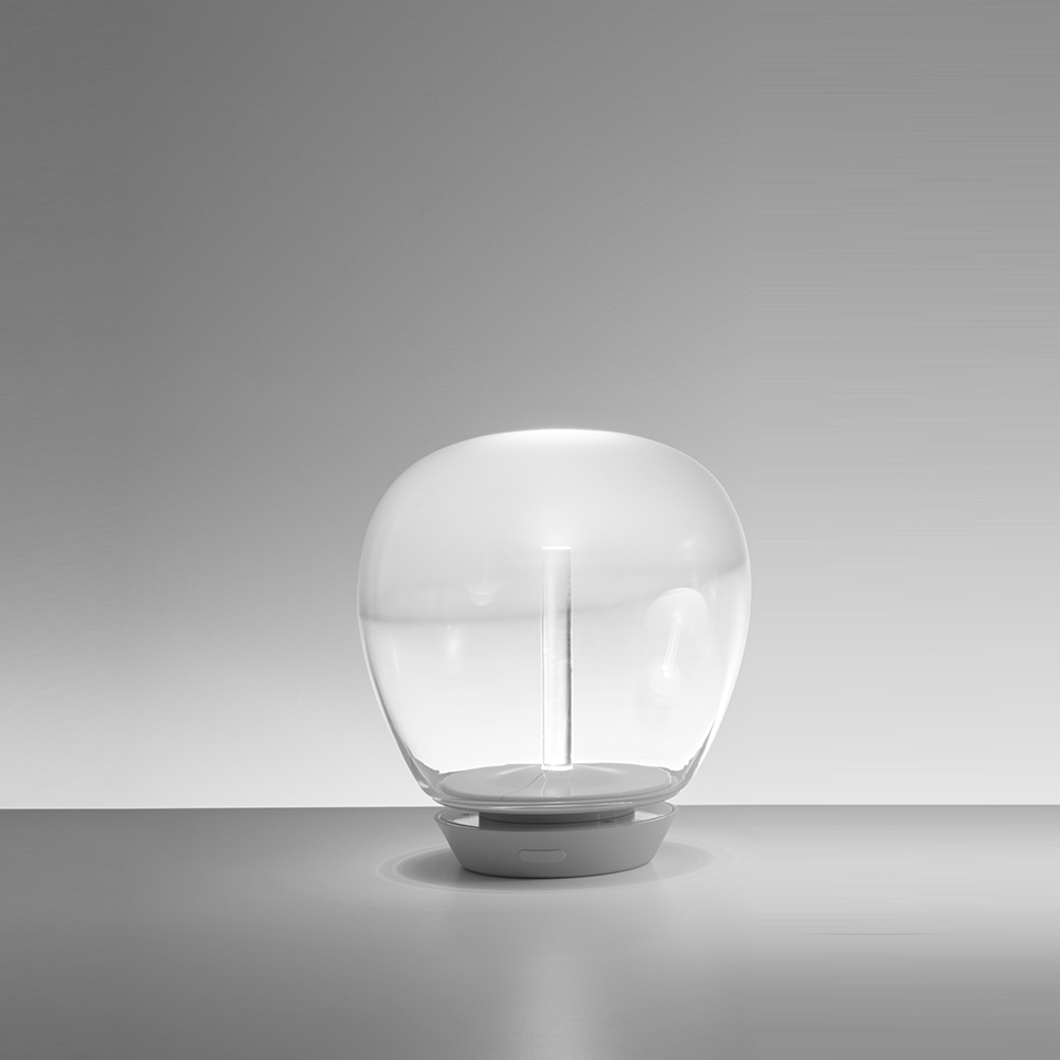 Artemide Empatia table lamp: rounded transparent glass diffuser on a compact grey base with a central LED stem