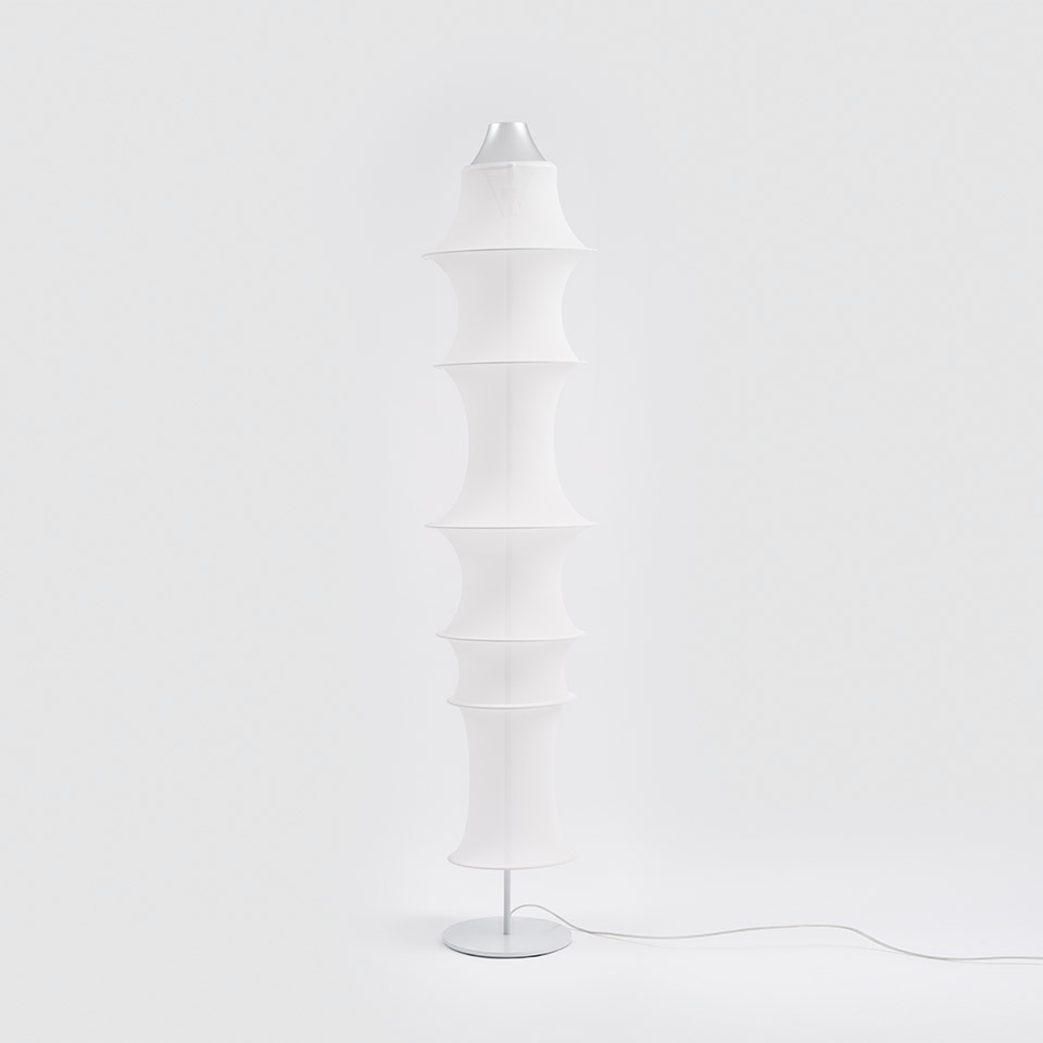 Lampada da terra Artemide Falkland Terra: alto paralume in tessuto bianco con anelli a clessidra sovrapposti su base rotonda in metallo