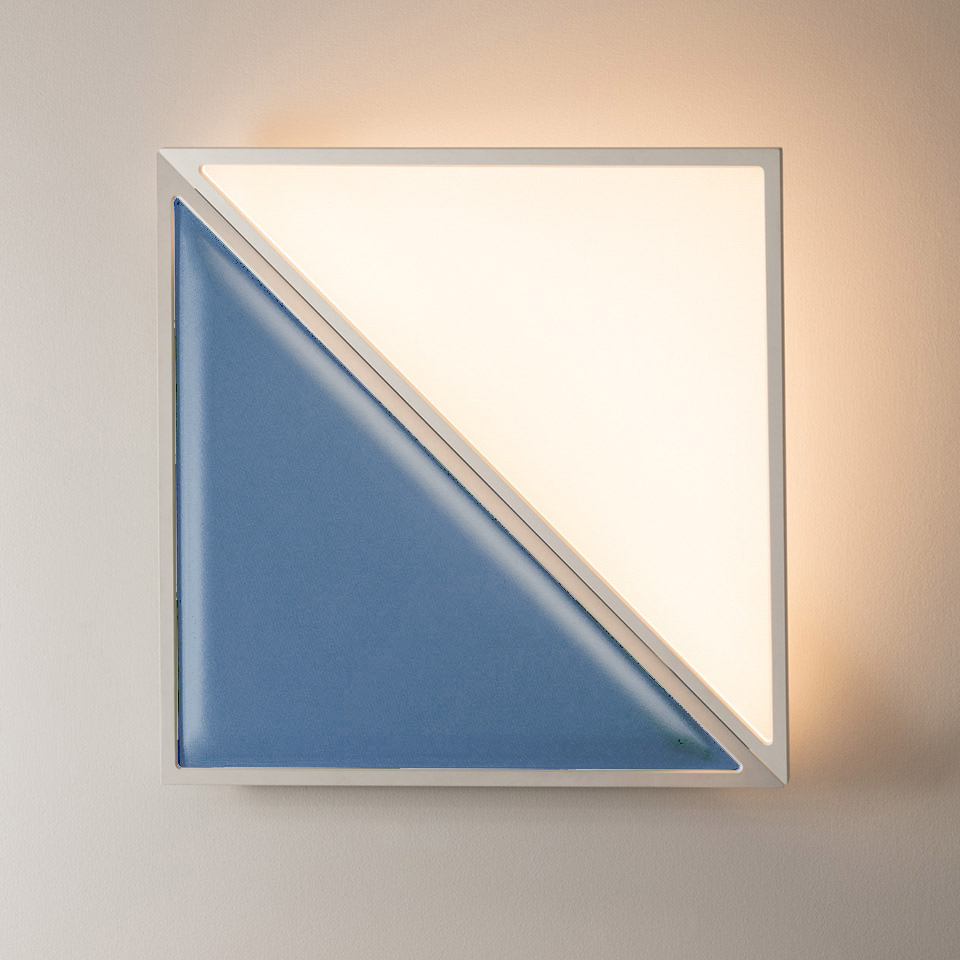Lampada da parete Artemide Flexia: cornice quadrata bianca con luce LED calda nel triangolo superiore destro, pannello ceramico blu nel triangolo inferiore sinistro