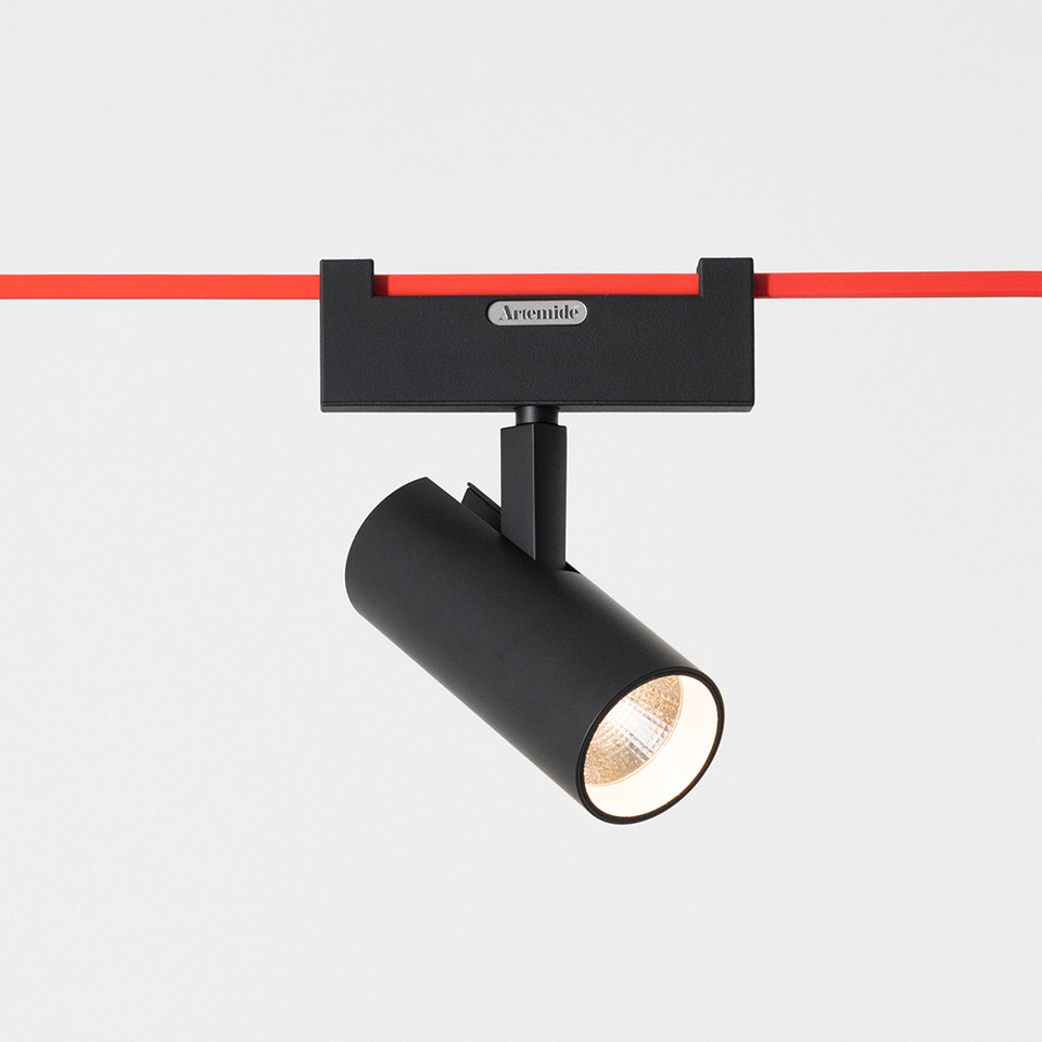 Artemide Funivia track spotlight: black cylindrical LED spot mounted on red magnetic track, tilted head for directional lighting