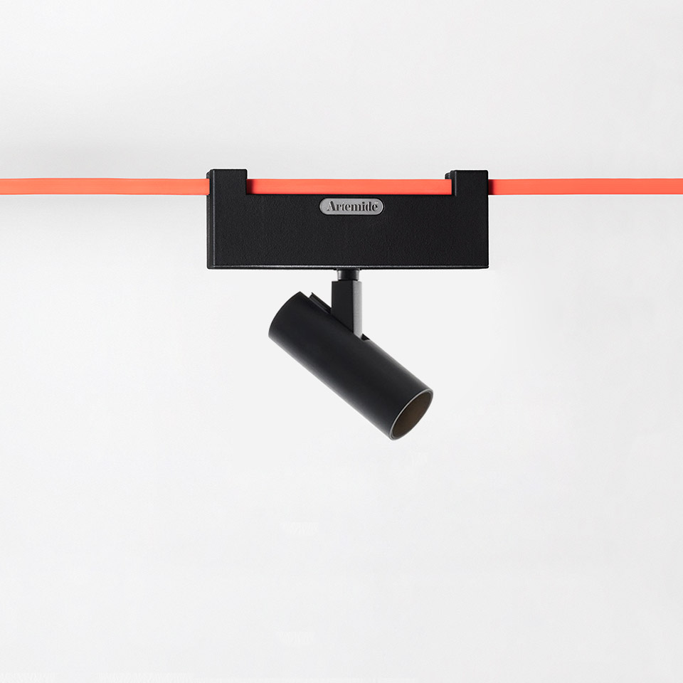 Artemide Funivia black track spotlight with adjustable cylindrical head mounted on a red cable rail system