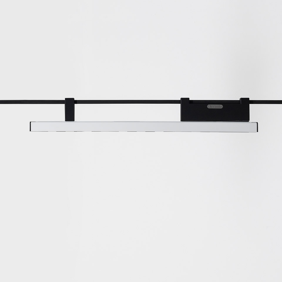 Artemide Funivia linear LED track light: slim white bar suspended from black cable rail system with black mounting brackets
