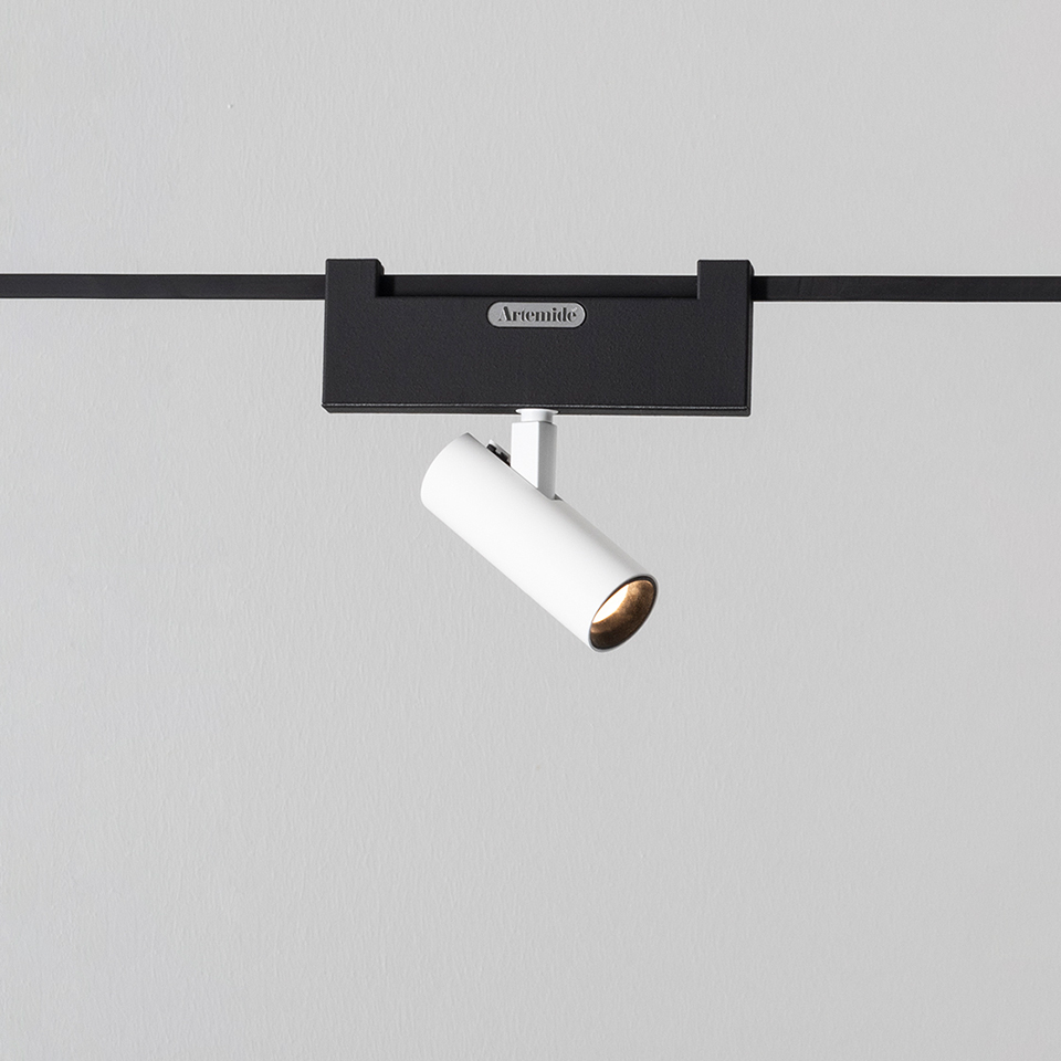 Artemide Funivia track spotlight: white cylindrical LED spot mounted on black track rail, tilted at an angle for directional lighting