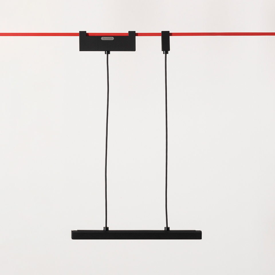 Artemide Funivia pendant lamp: slim black linear bar suspended by two black cables from a red ceiling track-mounted bracket