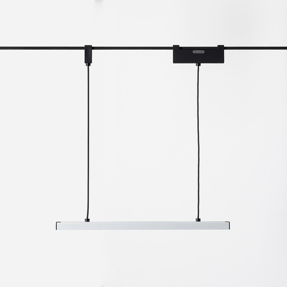 Artemide Funivia pendant lamp: slim white linear LED bar suspended by two black cables from a track-mounted black ceiling adapter