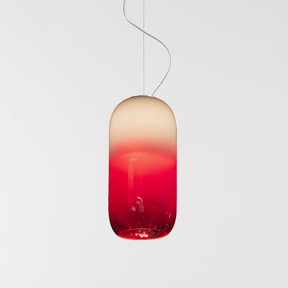 Artemide Gople pendant lamp: pill-shaped blown glass shade with gradient from warm white at top to vivid red at bottom, on silver cord