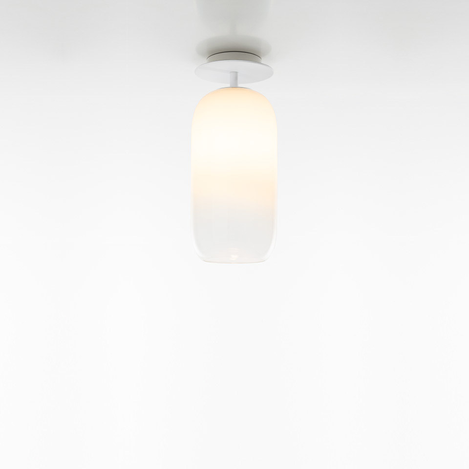 Artemide Gople ceiling lamp with elongated opal white glass diffuser mounted on a white circular ceiling rose