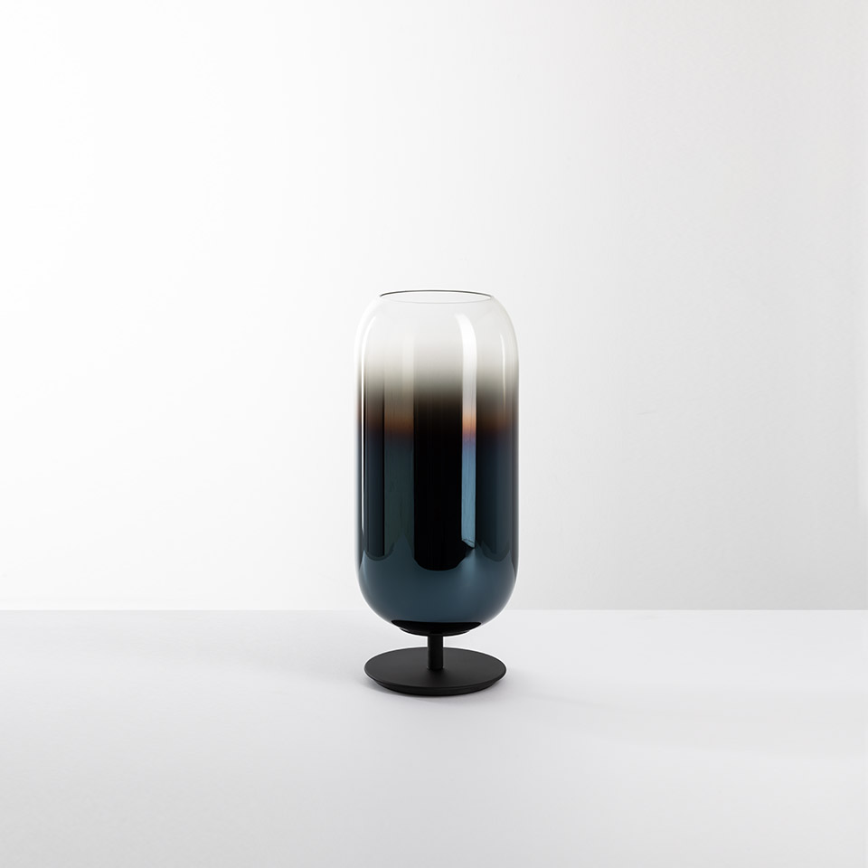 Artemide Gople table lamp: tall capsule-shaped blown glass shade with blue-to-clear gradient, on a round black metal base