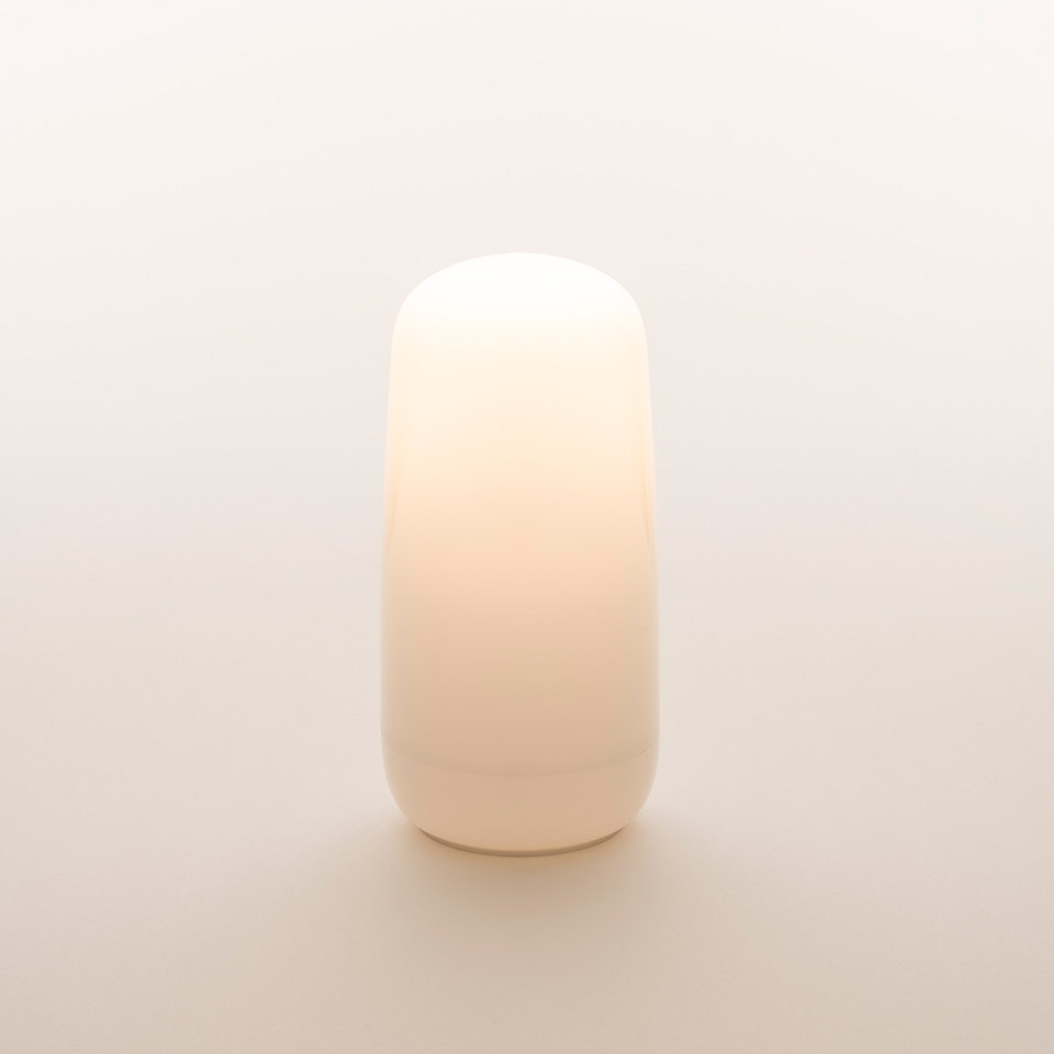 Lampada Artemide Gople Portable: diffusore in vetro soffiato opalino bianco compatto con sommità e base arrotondate, emette luce calda e soffusa