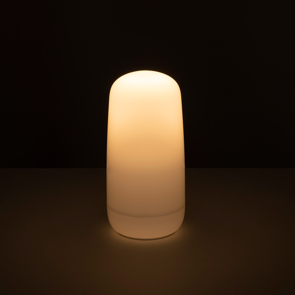 Lampada Artemide Gople Portable illuminata con luce bianca calda, con diffusore opalino cilindrico arrotondato su superficie scura - 2