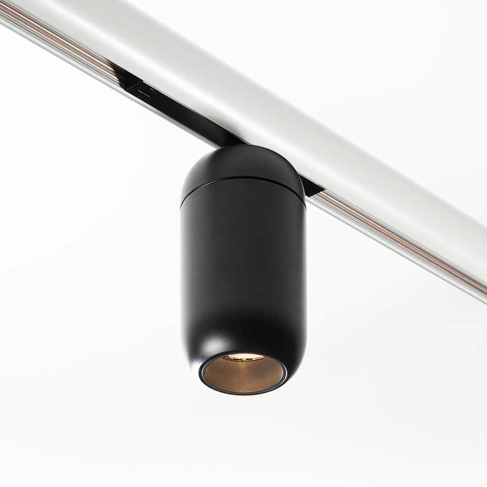 Faretto da binario Artemide Gople System: compatto corpo cilindrico nero a LED montato su binario argento, orientato verso il basso