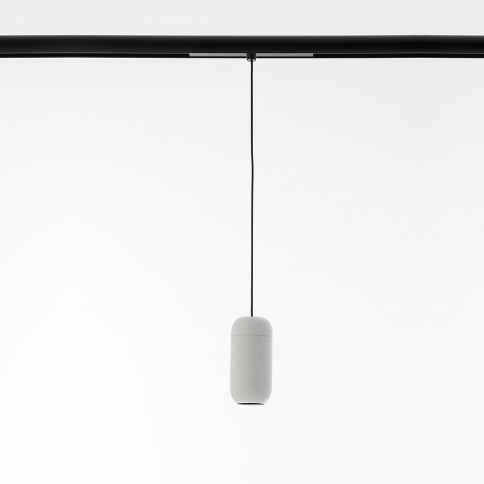 Lampada a sospensione Artemide Gople System: piccolo paralume bianco a capsula sospeso da un sottile cavo nero su binario nero a soffitto