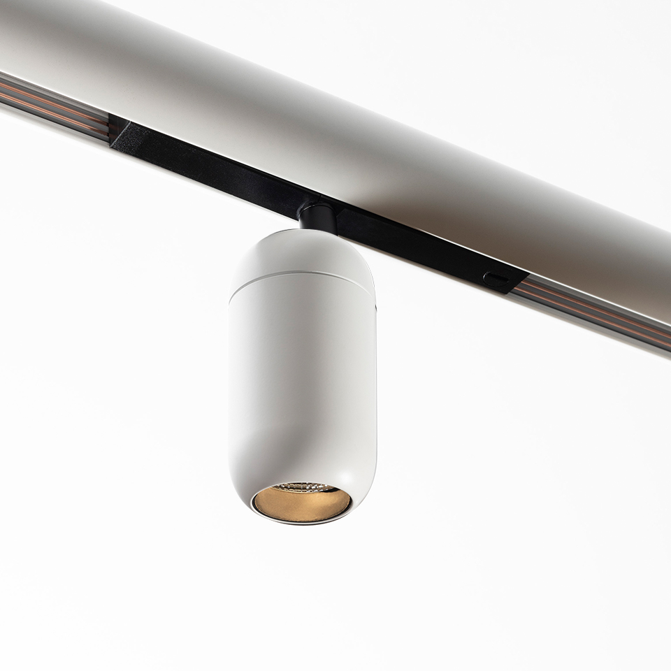 Faretto su binario Artemide Gople System: corpo cilindrico bianco con interno dorato, montato su binario a soffitto