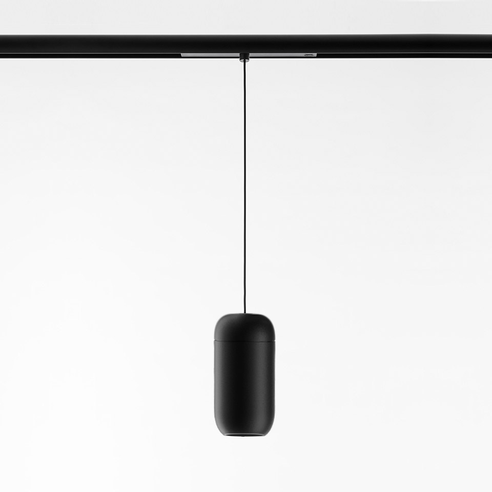 Lampada a sospensione Gople System di Artemide: diffusore nero opaco a forma di capsula sospeso da una guida a binario nera tramite un sottile cavo nero