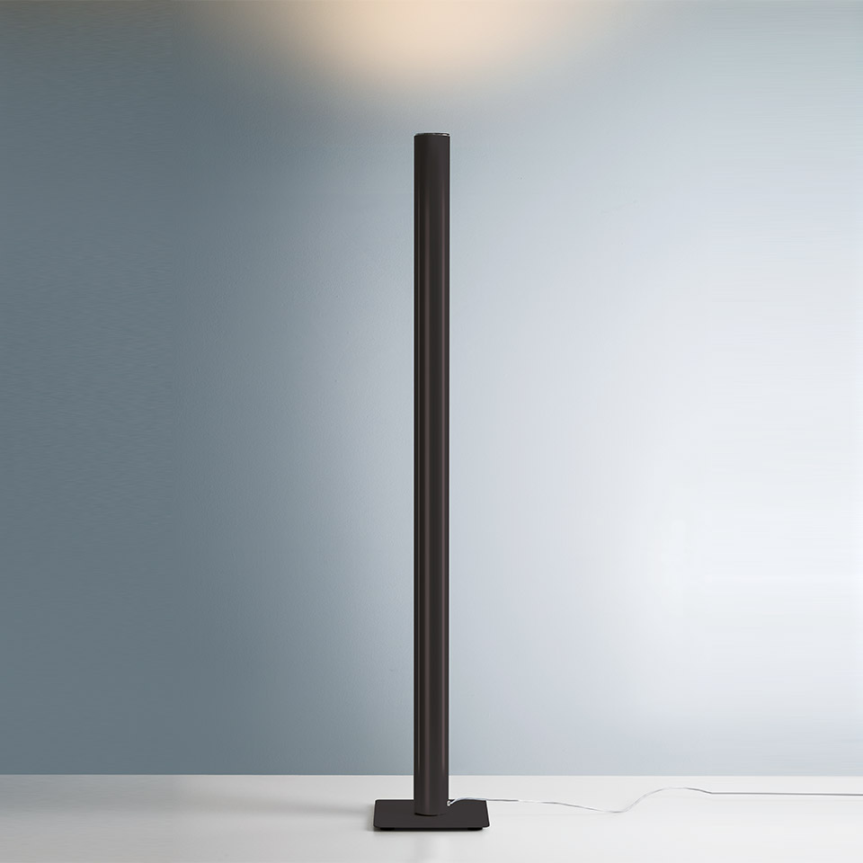 Lampada da terra Artemide Ilio nera, sottile colonna cilindrica su base quadrata, proietta luce indiretta calda verso l'alto sulla parete